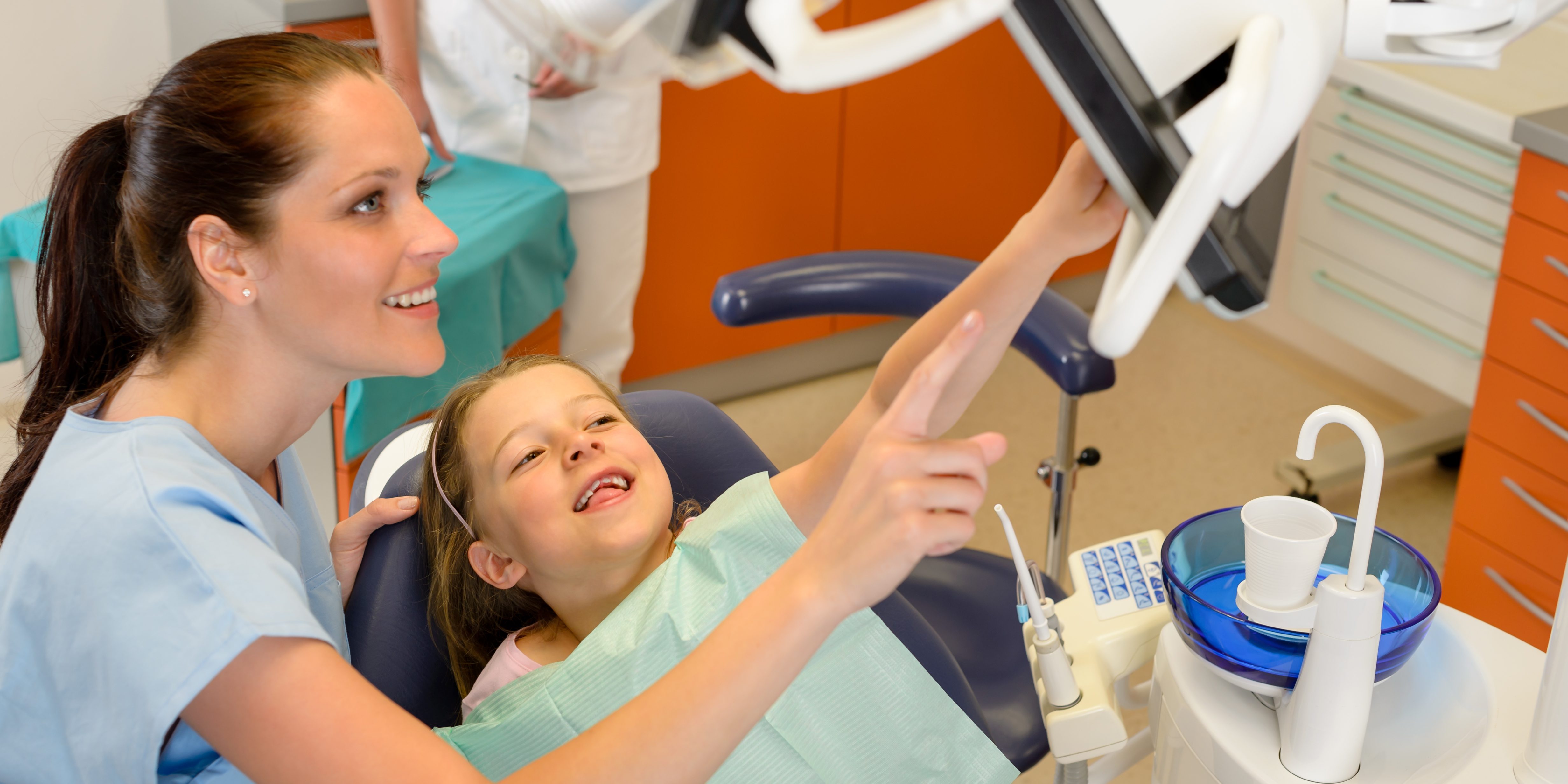 Dentist showing child dental procedure on monitor pediatric dentistry