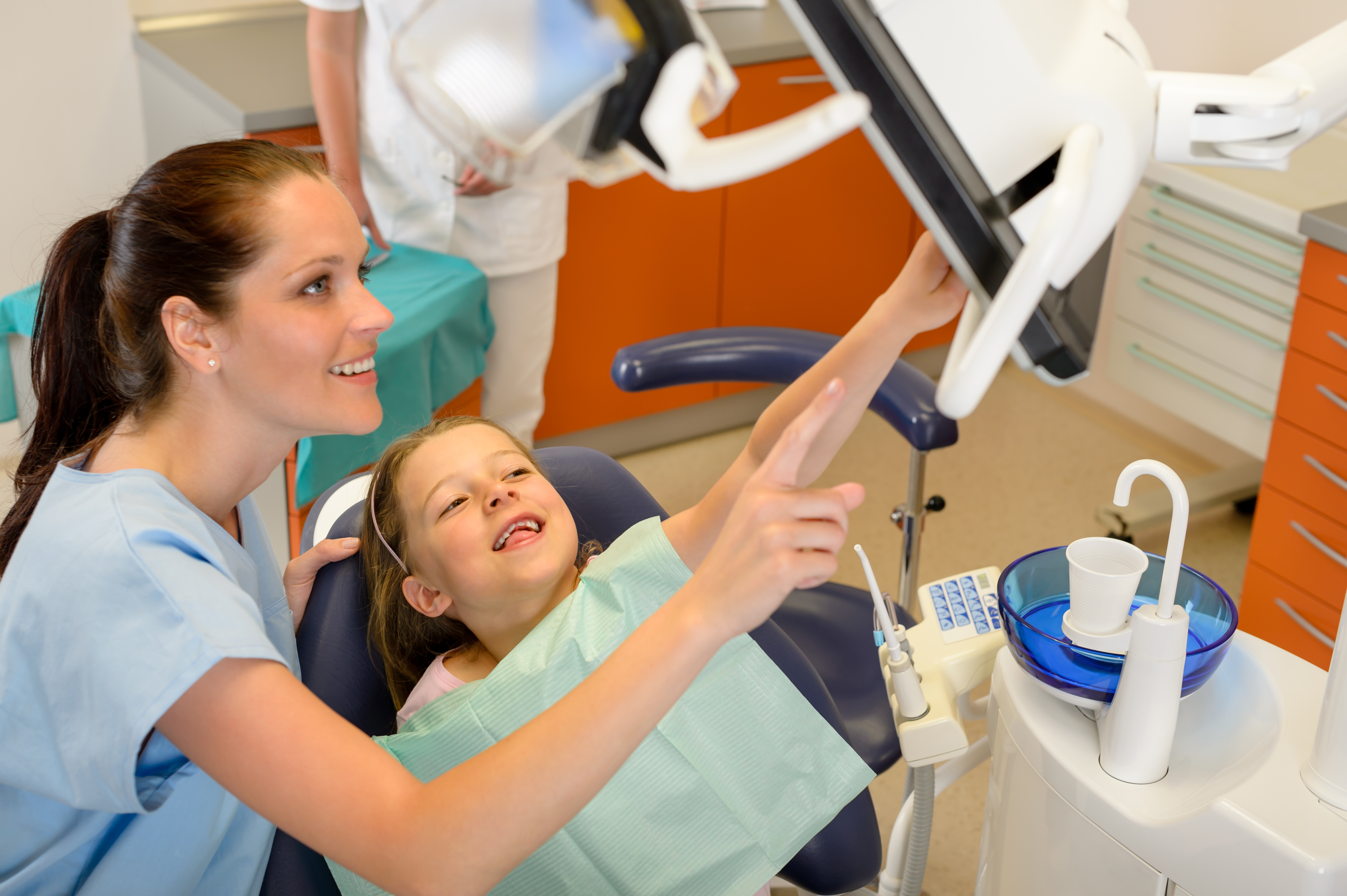 Dentist showing child dental procedure on monitor pediatric dentistry